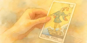 Mano sosteniendo la carta del tarot El Loco en un estilo de ilustración suave en tonos cálidos.